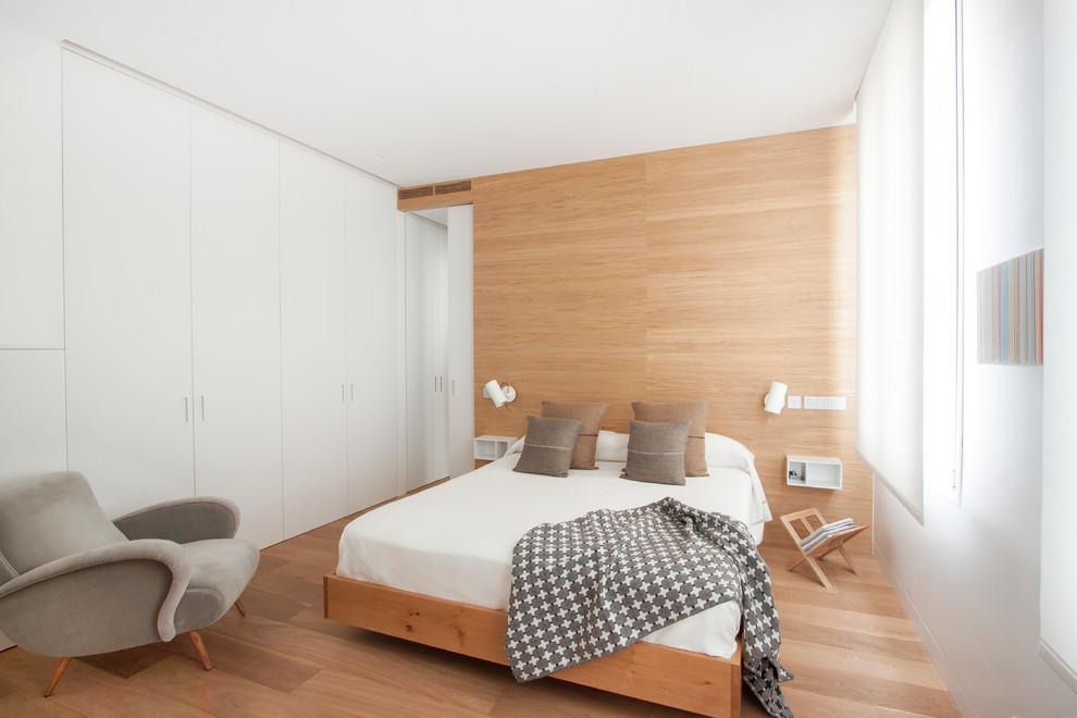 This is an example of a mid-sized scandinavian master bedroom in Madrid with light hardwood floors, brown walls and no fireplace.