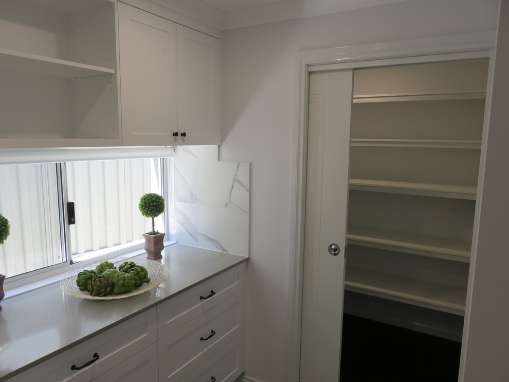 Design ideas for a mid-sized traditional single-wall kitchen pantry in Perth with shaker cabinets, white cabinets, quartz benchtops, white splashback, stone tile splashback, stainless steel appliances, dark hardwood floors, no island and brown floor.