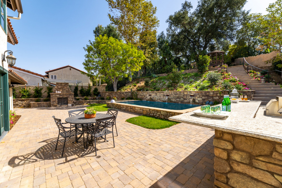 Inspiration for an expansive mediterranean backyard full sun garden in Los Angeles with a retaining wall and natural stone pavers.