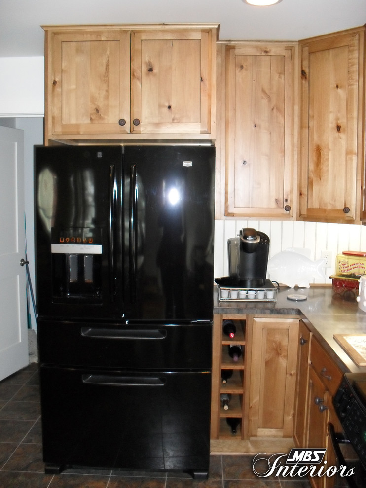 Inspiration for a rustic l-shaped eat-in kitchen remodel with a double-bowl sink, shaker cabinets, medium tone wood cabinets, solid surface countertops, yellow backsplash and black appliances