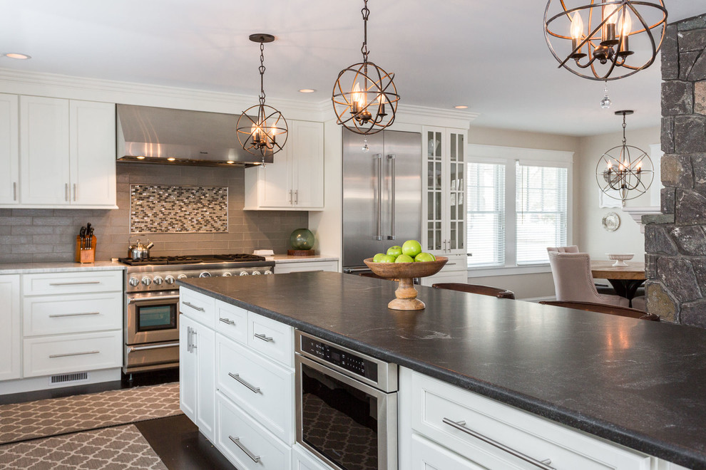 Example of a large transitional l-shaped dark wood floor and brown floor eat-in kitchen design in Boston with a farmhouse sink, recessed-panel cabinets, white cabinets, marble countertops, green backsplash, ceramic backsplash, stainless steel appliances, an island and black countertops