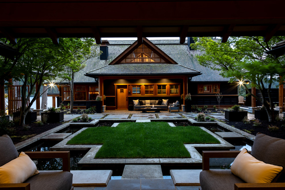 Expansive arts and crafts backyard patio in Vancouver with a water feature, natural stone pavers and a roof extension.