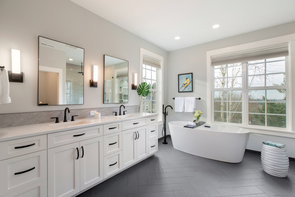 This is an example of a mid-sized transitional master bathroom in Portland with shaker cabinets, white cabinets, a freestanding tub, a curbless shower, ceramic tile, grey walls, an undermount sink, quartzite benchtops, white benchtops, a double vanity, a built-in vanity, grey floor and a hinged shower door.