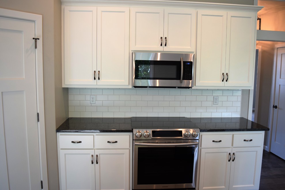 Inspiration for a mid-sized medium tone wood floor open concept kitchen remodel with white cabinets, granite countertops, subway tile backsplash, stainless steel appliances and an island