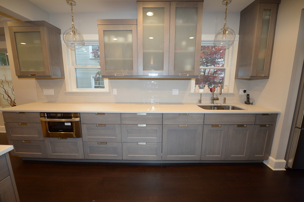This is an example of a large contemporary galley eat-in kitchen in Other with an undermount sink, shaker cabinets, grey cabinets, quartz benchtops, white splashback, glass tile splashback, stainless steel appliances, dark hardwood floors and no island.