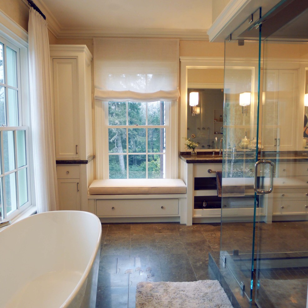 This is an example of a large traditional master bathroom in New York with yellow cabinets, a freestanding tub, a corner shower, brown floor, a hinged shower door, brown benchtops, yellow walls and porcelain floors.