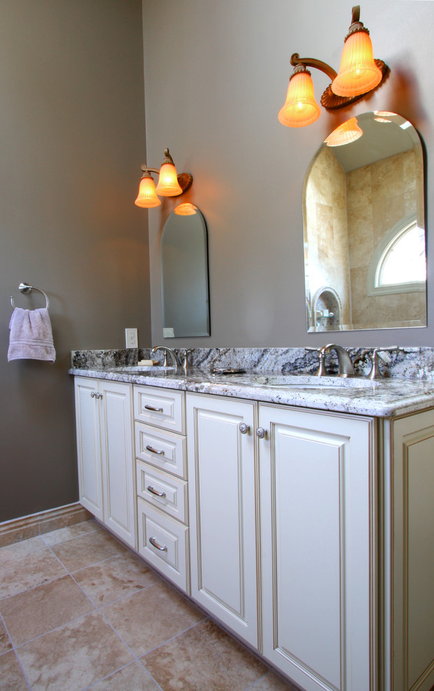 Photo of a mid-sized mediterranean master bathroom in Richmond with an undermount sink, raised-panel cabinets, white cabinets, granite benchtops, a drop-in tub, an alcove shower, a two-piece toilet, beige tile, stone tile, grey walls and travertine floors.