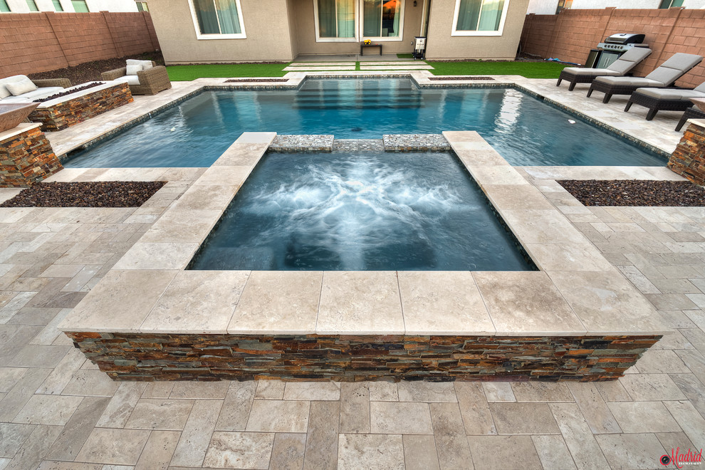 Photo of a mid-sized modern backyard rectangular natural pool in Phoenix with a hot tub and natural stone pavers.