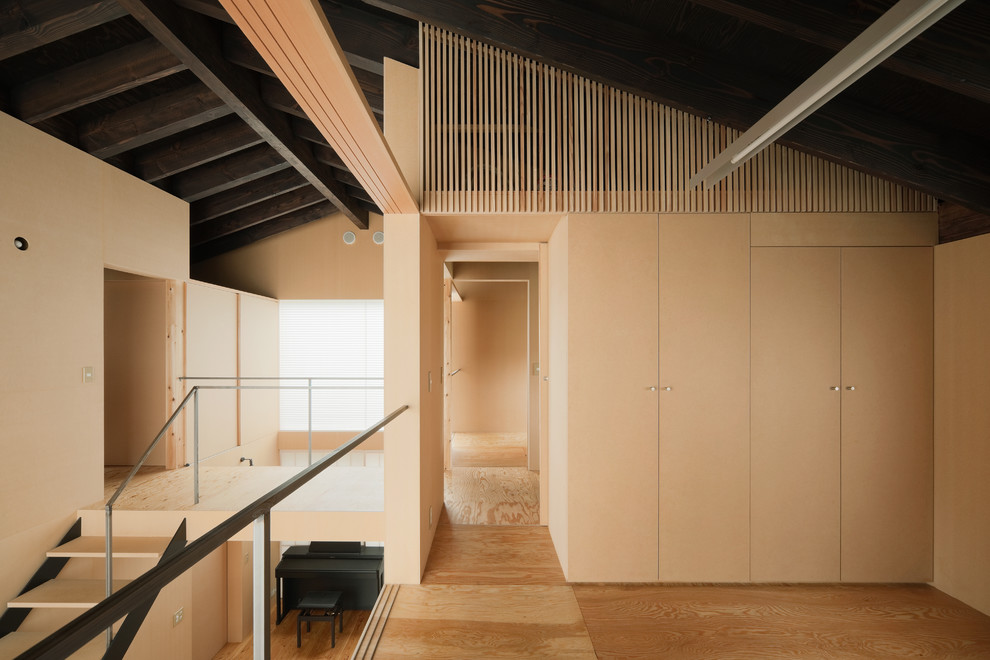 Asian loft-style bedroom in Tokyo Suburbs with beige walls, medium hardwood floors and beige floor.