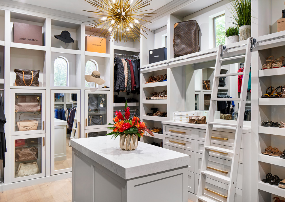 This is an example of a transitional women's walk-in wardrobe in Austin with shaker cabinets, grey cabinets, light hardwood floors and brown floor.