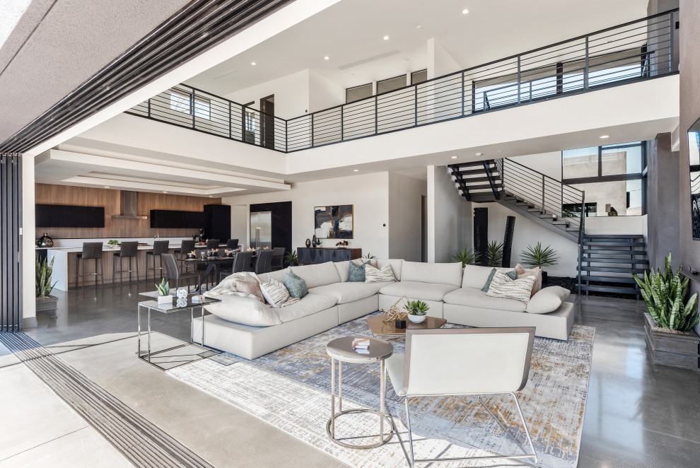 Large contemporary open concept living room in Las Vegas with white walls, grey floor and concrete floors.