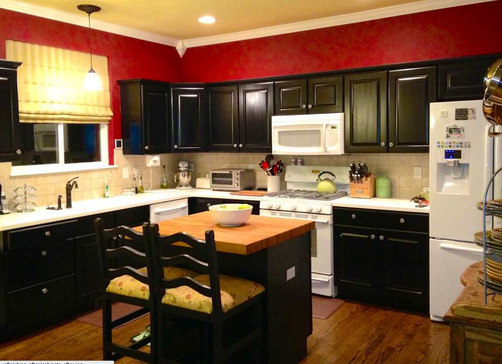Kitchen - medium tone wood floor kitchen idea in Denver with black cabinets, beige backsplash and white appliances