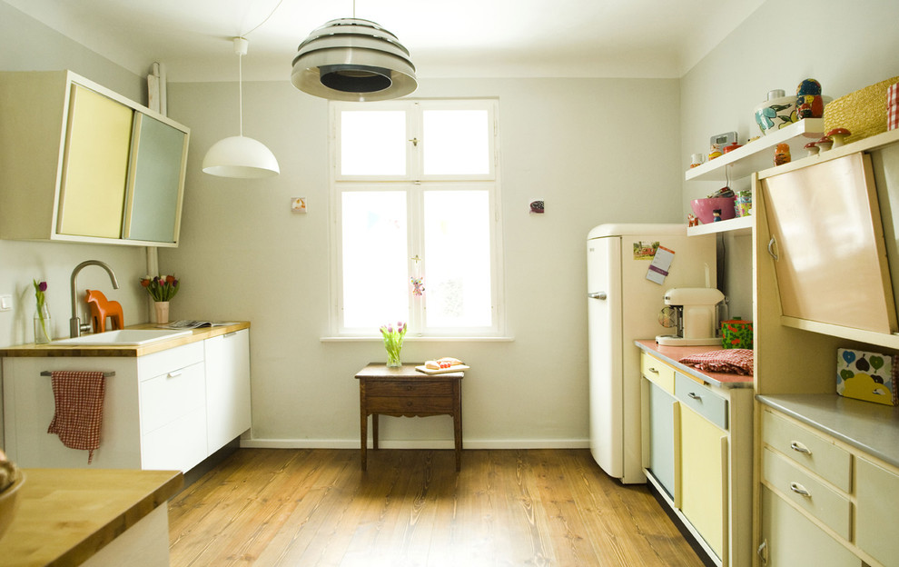 This is an example of a mid-sized scandinavian separate kitchen in Berlin with a farmhouse sink, medium hardwood floors and no island.