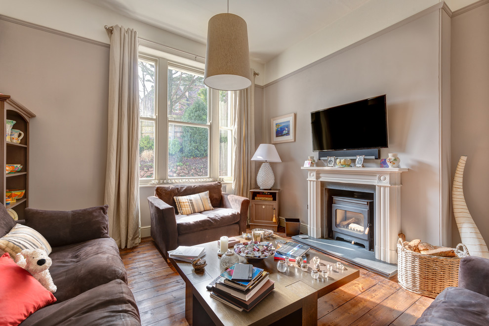 This is an example of a mid-sized transitional open concept living room in Devon with beige walls, medium hardwood floors, a standard fireplace, a plaster fireplace surround and a wall-mounted tv.