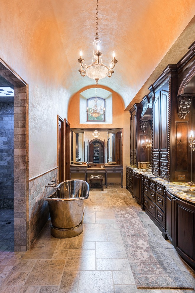 Large mediterranean master bathroom in Austin with an undermount sink, recessed-panel cabinets, dark wood cabinets, a freestanding tub, gray tile and beige walls.