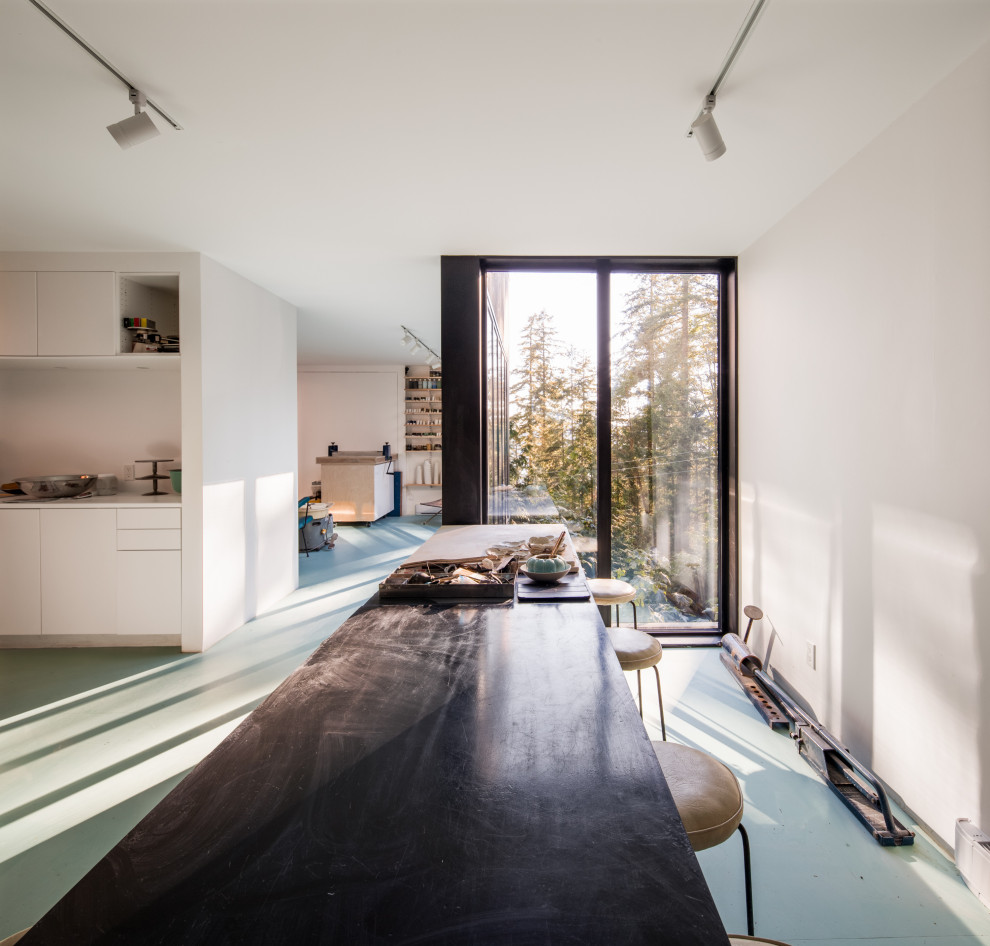 Cette photo montre un bureau tendance de type studio avec un mur blanc, sol en béton ciré et un sol bleu.