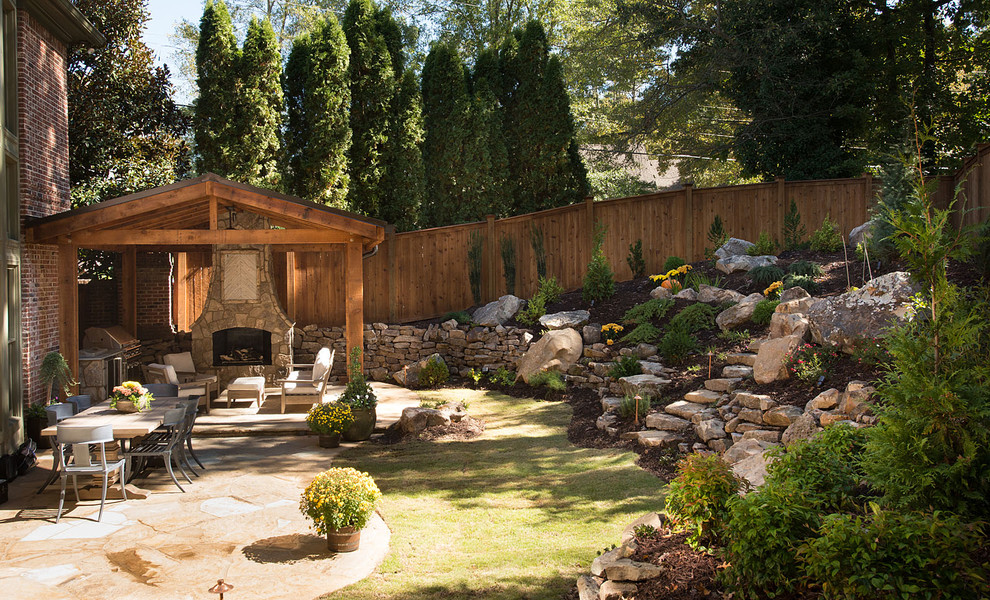 This is an example of a large mediterranean backyard patio in Atlanta with a fire feature, natural stone pavers and a pergola.