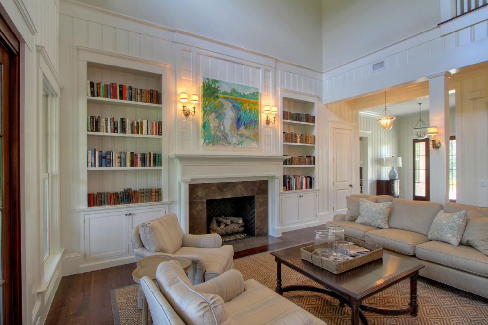 This is an example of a traditional family room in Atlanta with a library, white walls, dark hardwood floors, a standard fireplace and no tv.
