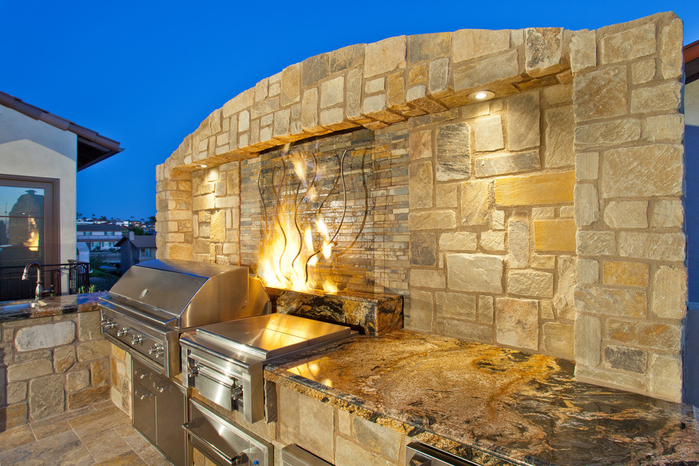 Photo of a large mediterranean courtyard patio in San Diego with an outdoor kitchen, natural stone pavers and no cover.