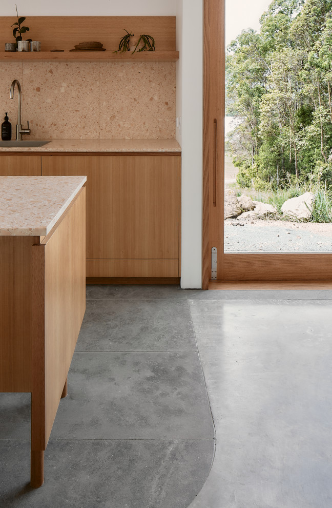 Inspiration for a small modern single-wall open plan kitchen in Sunshine Coast with a single-bowl sink, light wood cabinets, terrazzo benchtops, pink splashback, stone tile splashback, black appliances, limestone floors, with island, grey floor and pink benchtop.
