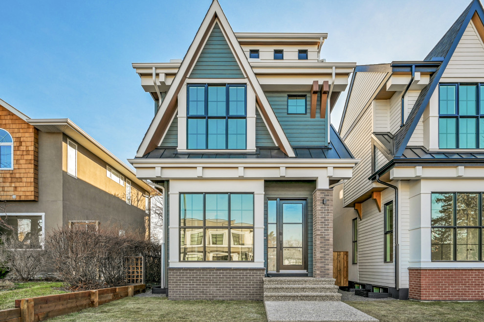 This is an example of a small country two-storey brick grey house exterior in Calgary with a gable roof and a shingle roof.