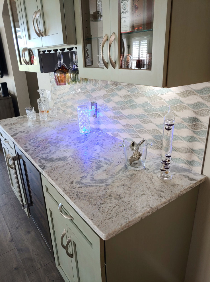 Photo of a small transitional galley home bar in Tampa with shaker cabinets, green cabinets, quartzite benchtops, multi-coloured splashback, glass tile splashback and grey benchtop.