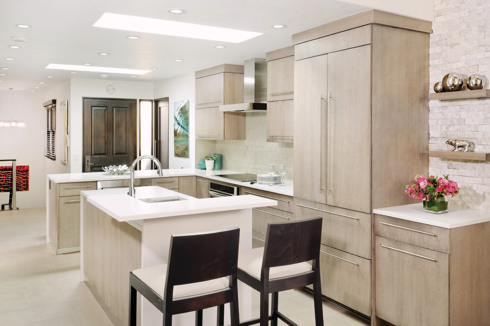 Small trendy l-shaped kitchen photo in Denver with an undermount sink, flat-panel cabinets, light wood cabinets, white backsplash, subway tile backsplash, paneled appliances, white walls and an island
