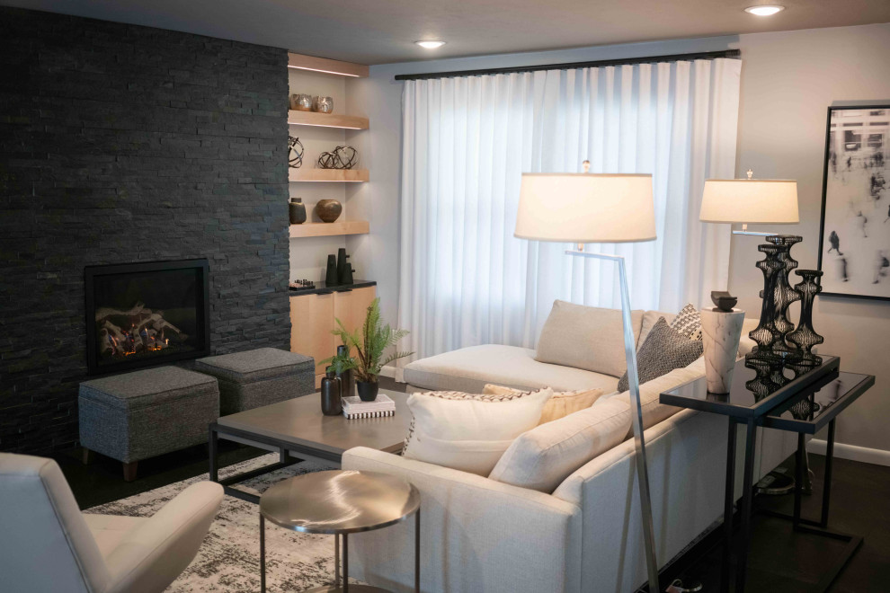 Свежая идея для дизайна: большая открытая гостиная комната в стиле ретро с серыми стенами, полом из винила, стандартным камином, фасадом камина из камня и черным полом - отличное фото интерьера
