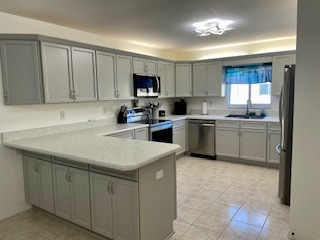 Example of a large u-shaped eat-in kitchen design with flat-panel cabinets, gray cabinets, laminate countertops and a peninsula