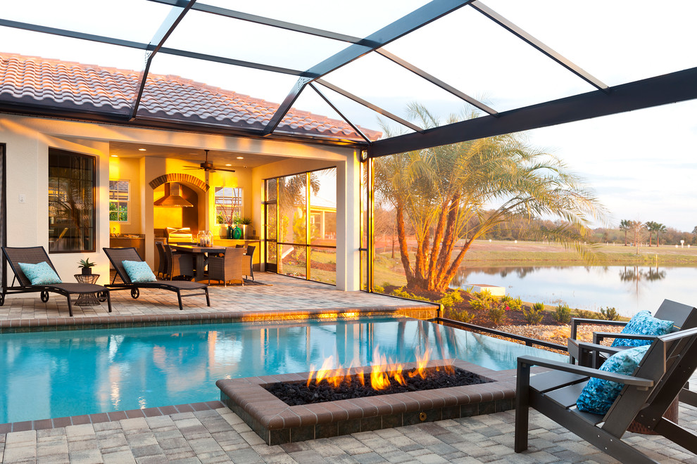 This is an example of a large traditional backyard patio in Tampa with a fire feature, concrete pavers and a roof extension.