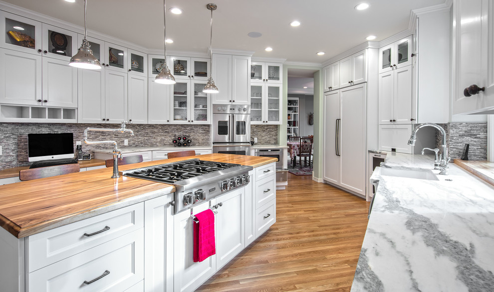 This is an example of a large transitional u-shaped separate kitchen in San Diego with a farmhouse sink, shaker cabinets, white cabinets, wood benchtops, grey splashback, stone tile splashback, stainless steel appliances, medium hardwood floors and with island.