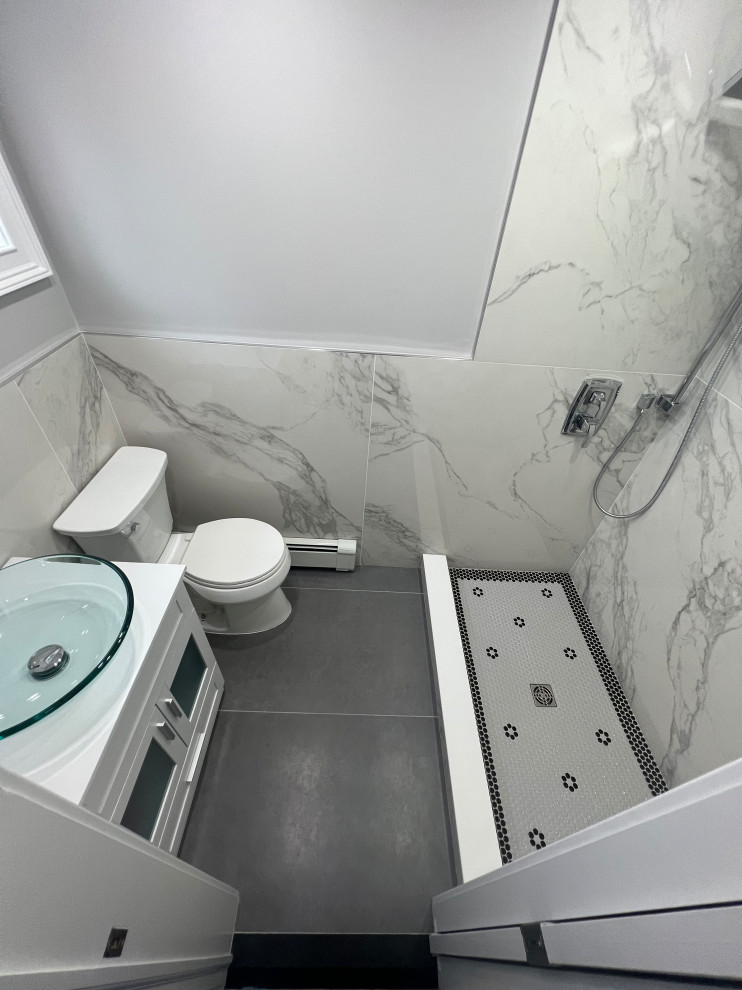 This is an example of a mid-sized modern powder room in New York with a one-piece toilet, white tile, white walls, a wall-mount sink and grey floor.