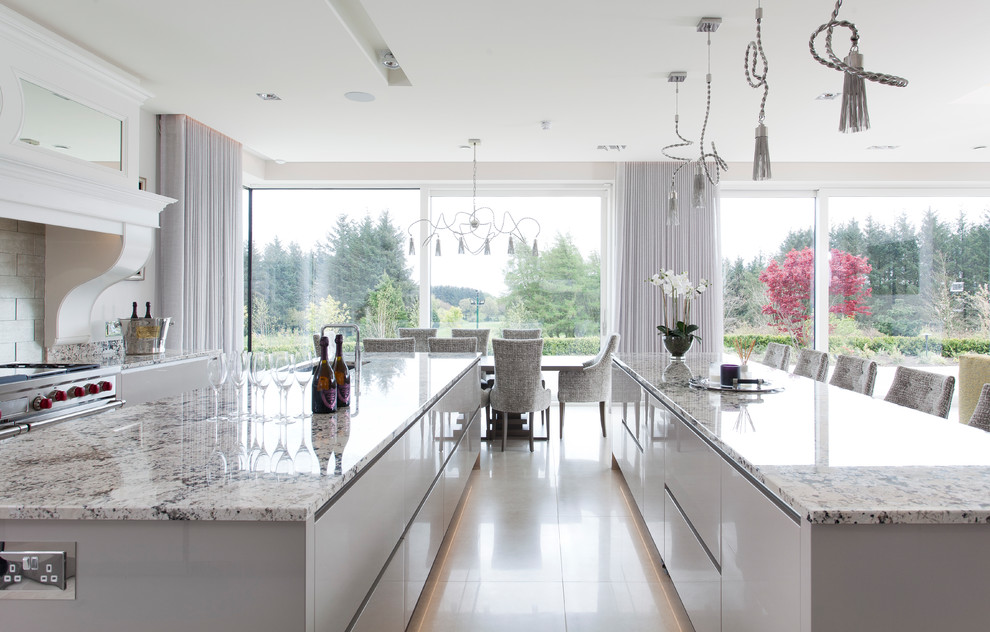 Photo of an expansive modern l-shaped open plan kitchen in Glasgow with an undermount sink, flat-panel cabinets, grey cabinets, marble benchtops, grey splashback, marble splashback, stainless steel appliances, porcelain floors, multiple islands, beige floor and grey benchtop.