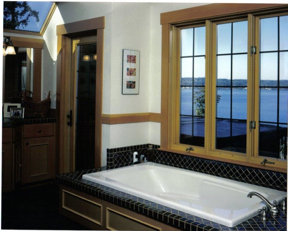 Example of a mid-sized transitional master black tile and porcelain tile drop-in bathtub design with recessed-panel cabinets, light wood cabinets and white walls