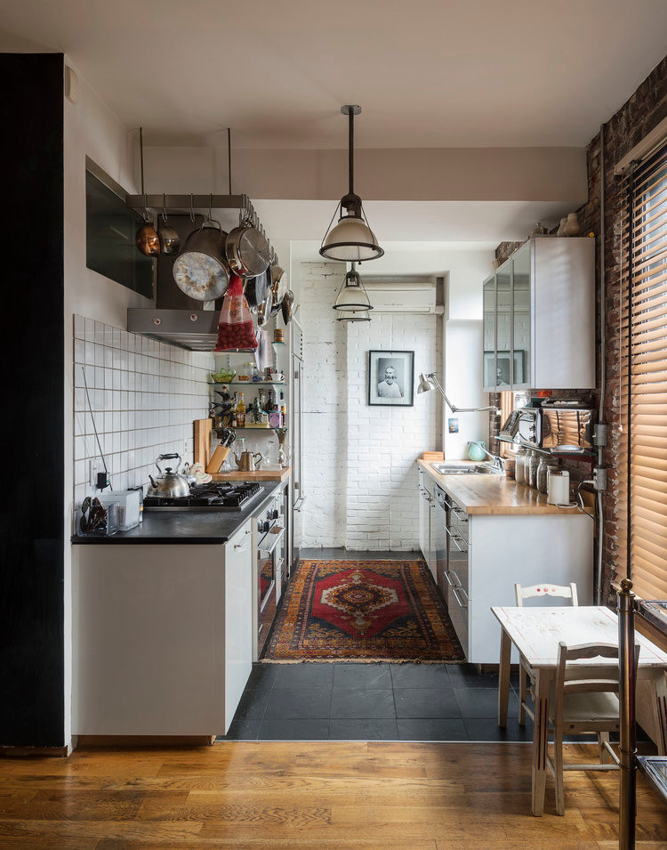 This is an example of a small eclectic galley eat-in kitchen in New York with a drop-in sink, flat-panel cabinets, white cabinets, soapstone benchtops, white splashback, ceramic splashback, stainless steel appliances, slate floors and no island.