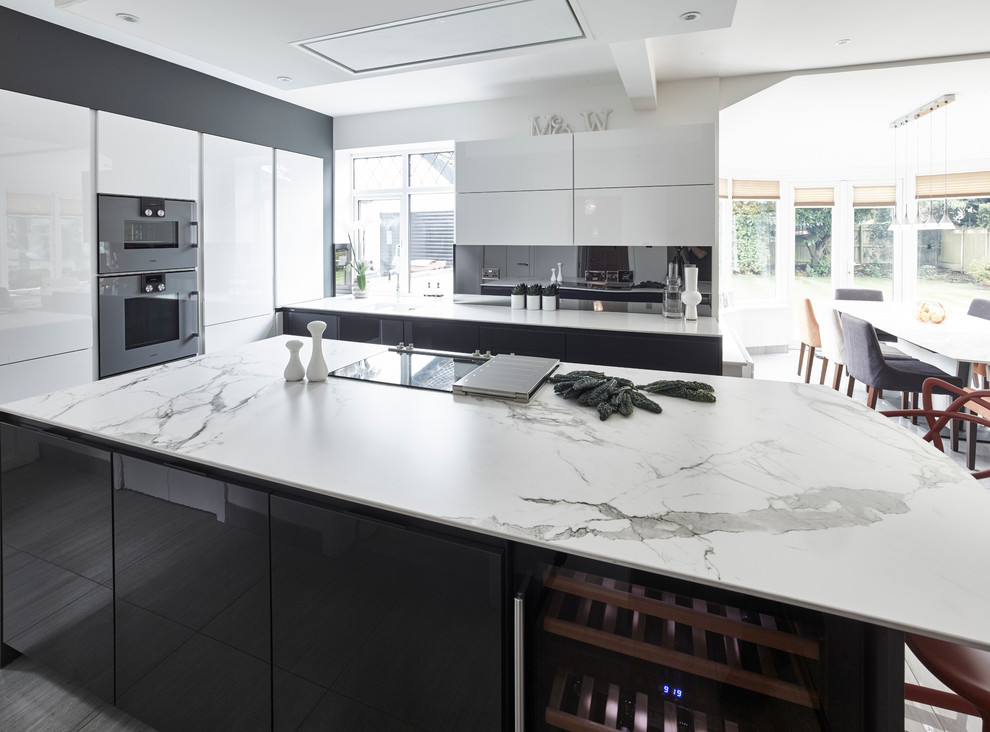 This is an example of a large contemporary l-shaped open plan kitchen in Other with flat-panel cabinets, quartz benchtops, grey splashback, mirror splashback, with island, white cabinets, coloured appliances, porcelain floors, beige floor and white benchtop.