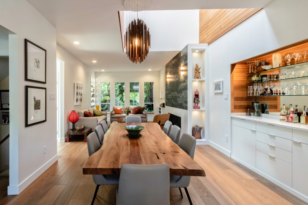 Inspiration for a mid-sized contemporary dining room in Vancouver with white walls, medium hardwood floors, a standard fireplace and brown floor.