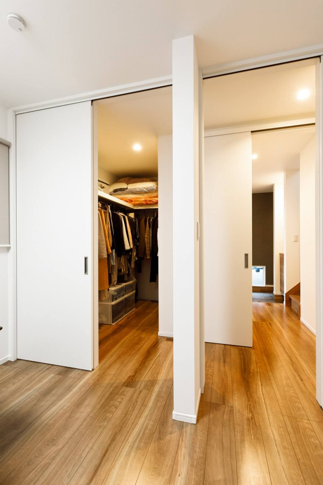 Bild på ett mellanstort industriellt walk-in-closet för könsneutrala, med släta luckor, vita skåp, mellanmörkt trägolv och brunt golv