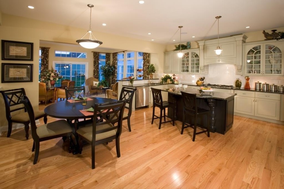 Large transitional u-shaped light wood floor eat-in kitchen photo in Philadelphia with an undermount sink, raised-panel cabinets, gray cabinets, granite countertops, white backsplash, porcelain backsplash, stainless steel appliances and an island