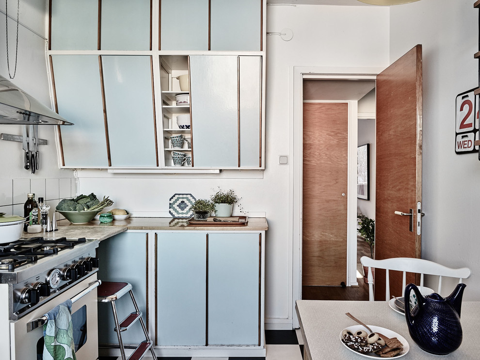 Photo of a small scandinavian l-shaped eat-in kitchen in Other with flat-panel cabinets, blue cabinets, wood benchtops, stainless steel appliances, ceramic floors and no island.