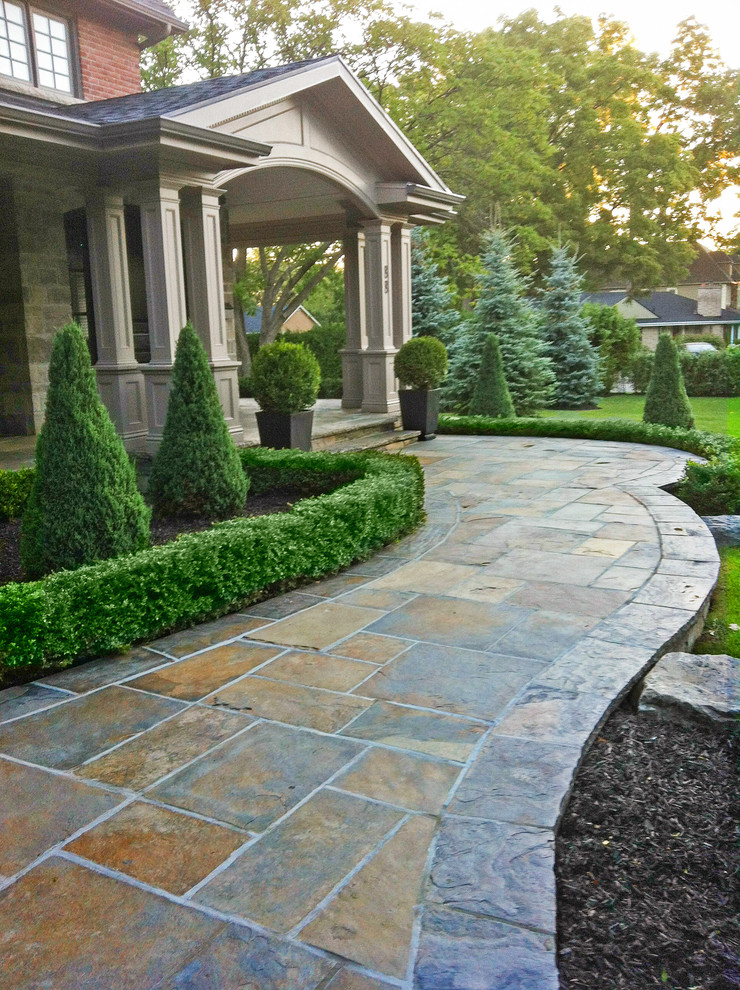 This is an example of a mid-sized traditional front yard full sun garden in Toronto with natural stone pavers and a garden path.