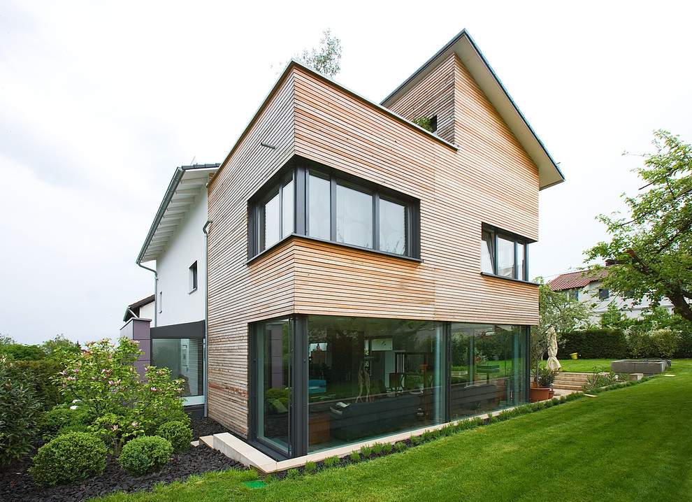 This is an example of a large contemporary two-storey exterior in Stuttgart with wood siding.