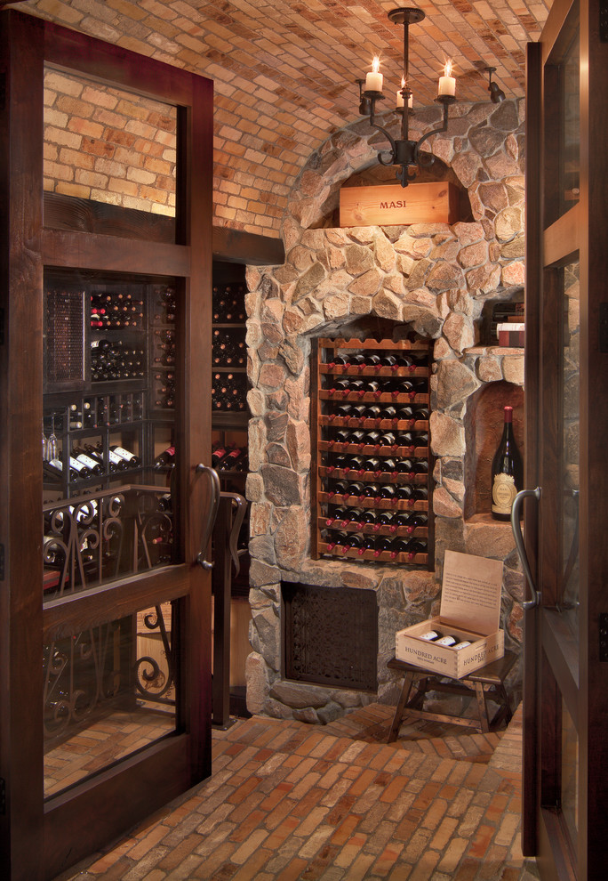 Inspiration for a mid-sized mediterranean wine cellar in Phoenix with brick floors, storage racks and beige floor.