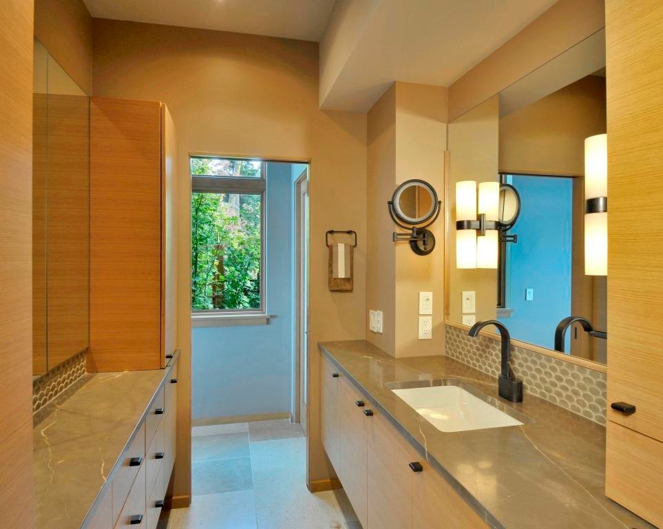 Mid-sized contemporary women's dressing room in Seattle with flat-panel cabinets, light wood cabinets and limestone floors.