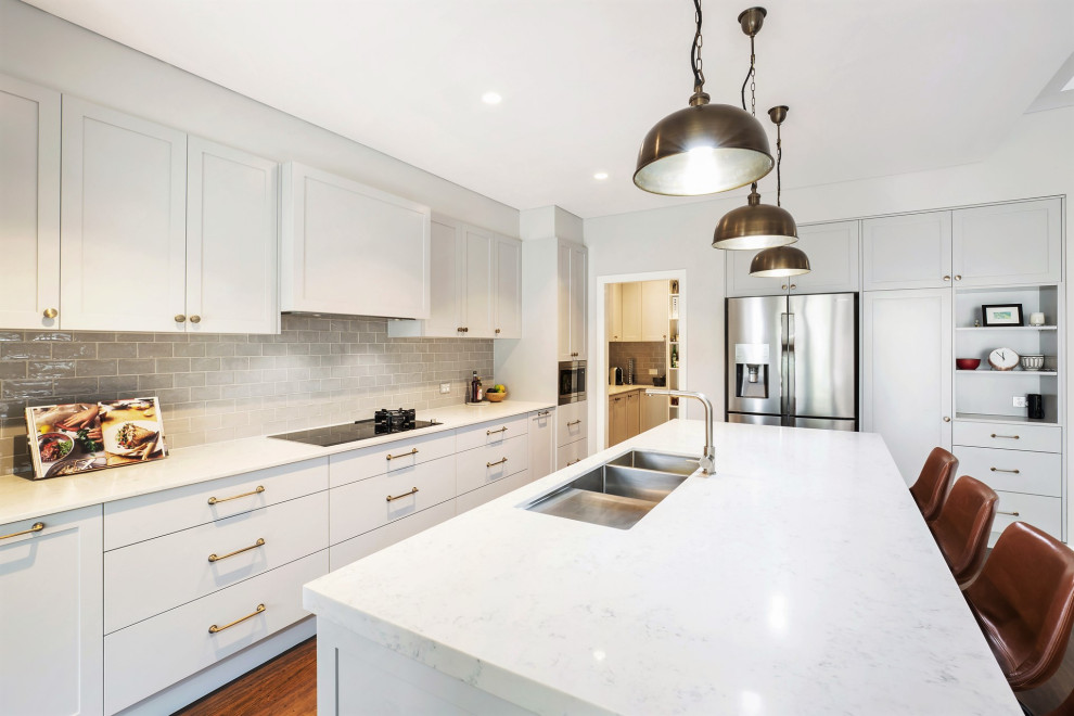 Inspiration for a large transitional galley open plan kitchen in Sydney with an undermount sink, shaker cabinets, grey cabinets, marble benchtops, grey splashback, subway tile splashback, stainless steel appliances, light hardwood floors, with island, brown floor and grey benchtop.