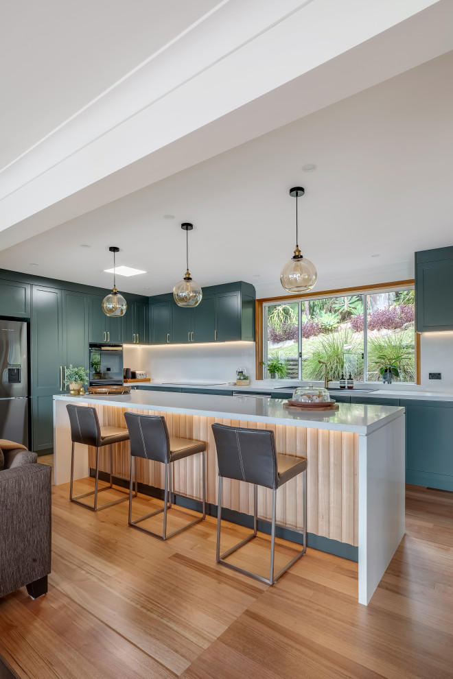 Inspiration for a large transitional l-shaped medium tone wood floor and multicolored floor eat-in kitchen remodel in Sydney with a drop-in sink, shaker cabinets, green cabinets, quartz countertops, white backsplash, quartz backsplash, black appliances, an island and white countertops