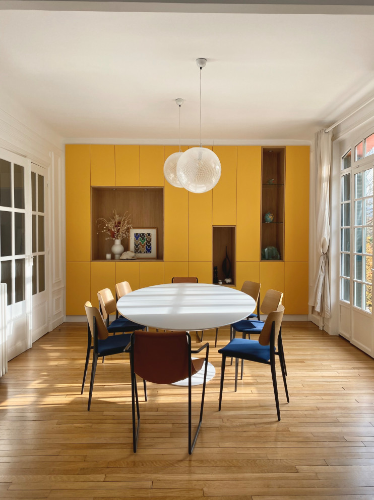 Cette photo montre une grande salle à manger tendance fermée avec parquet clair, un mur blanc et un sol beige.