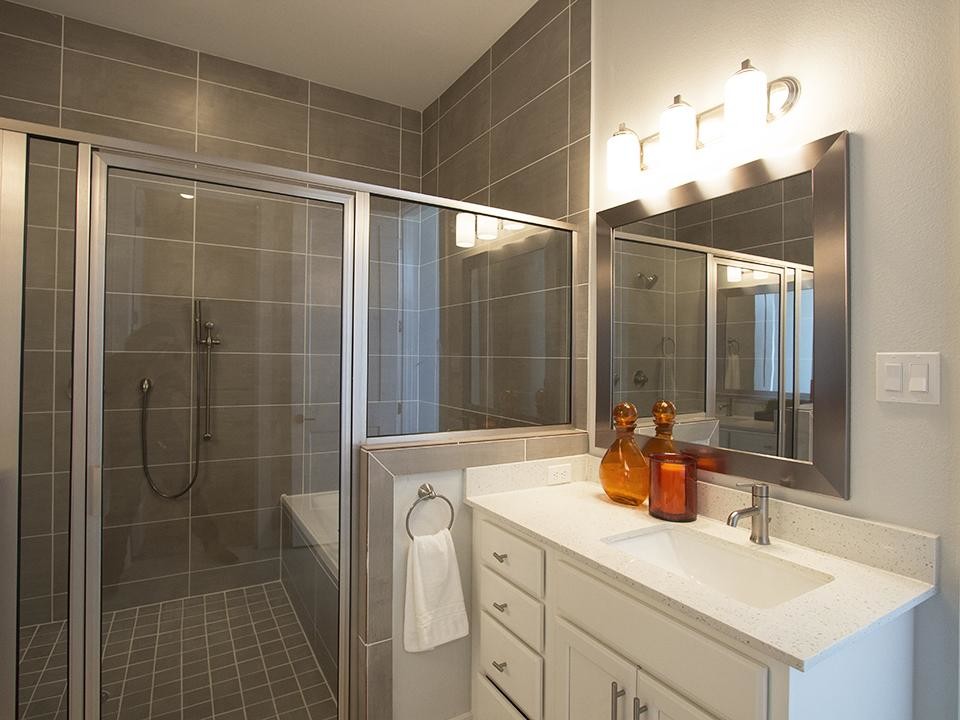Inspiration for a mid-sized contemporary master bathroom in Houston with recessed-panel cabinets, white cabinets, an alcove tub, an alcove shower, gray tile, ceramic tile, grey walls, ceramic floors, an undermount sink, terrazzo benchtops, beige floor and a hinged shower door.