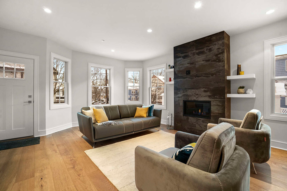 This is an example of a large modern loft-style living room in Boston with medium hardwood floors, a stone fireplace surround, a wall-mounted tv and brown floor.