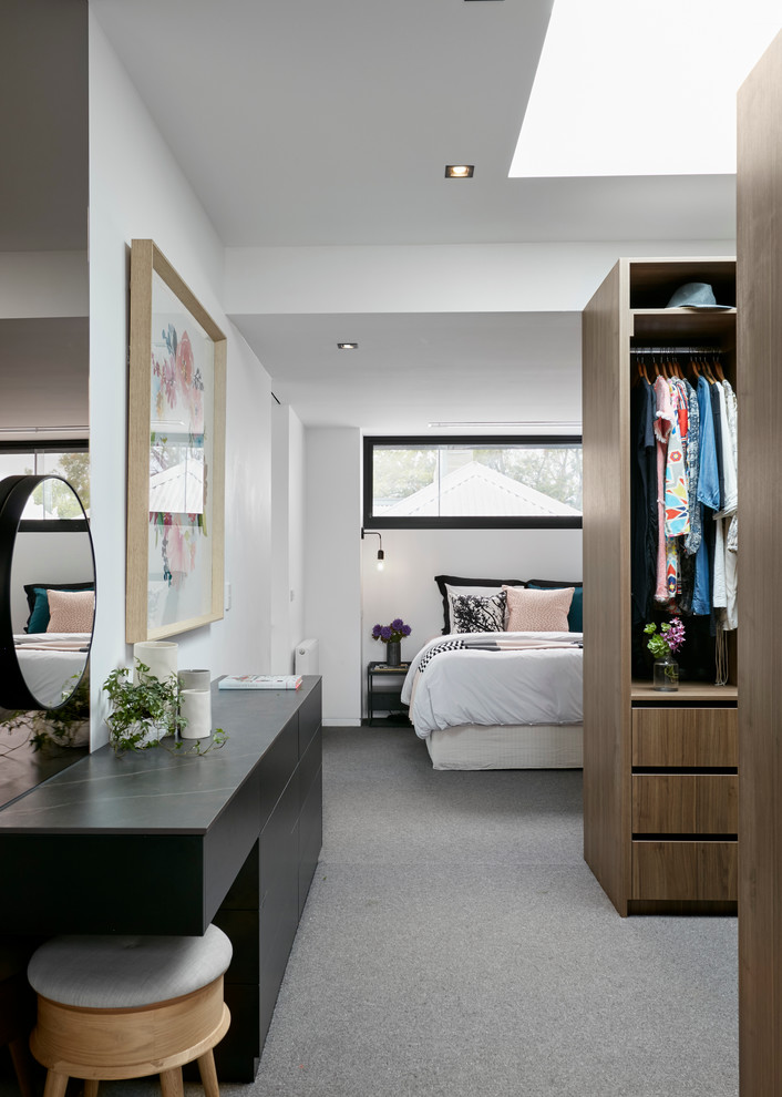 Photo of a contemporary women's dressing room in Melbourne with open cabinets, medium wood cabinets, carpet and grey floor.